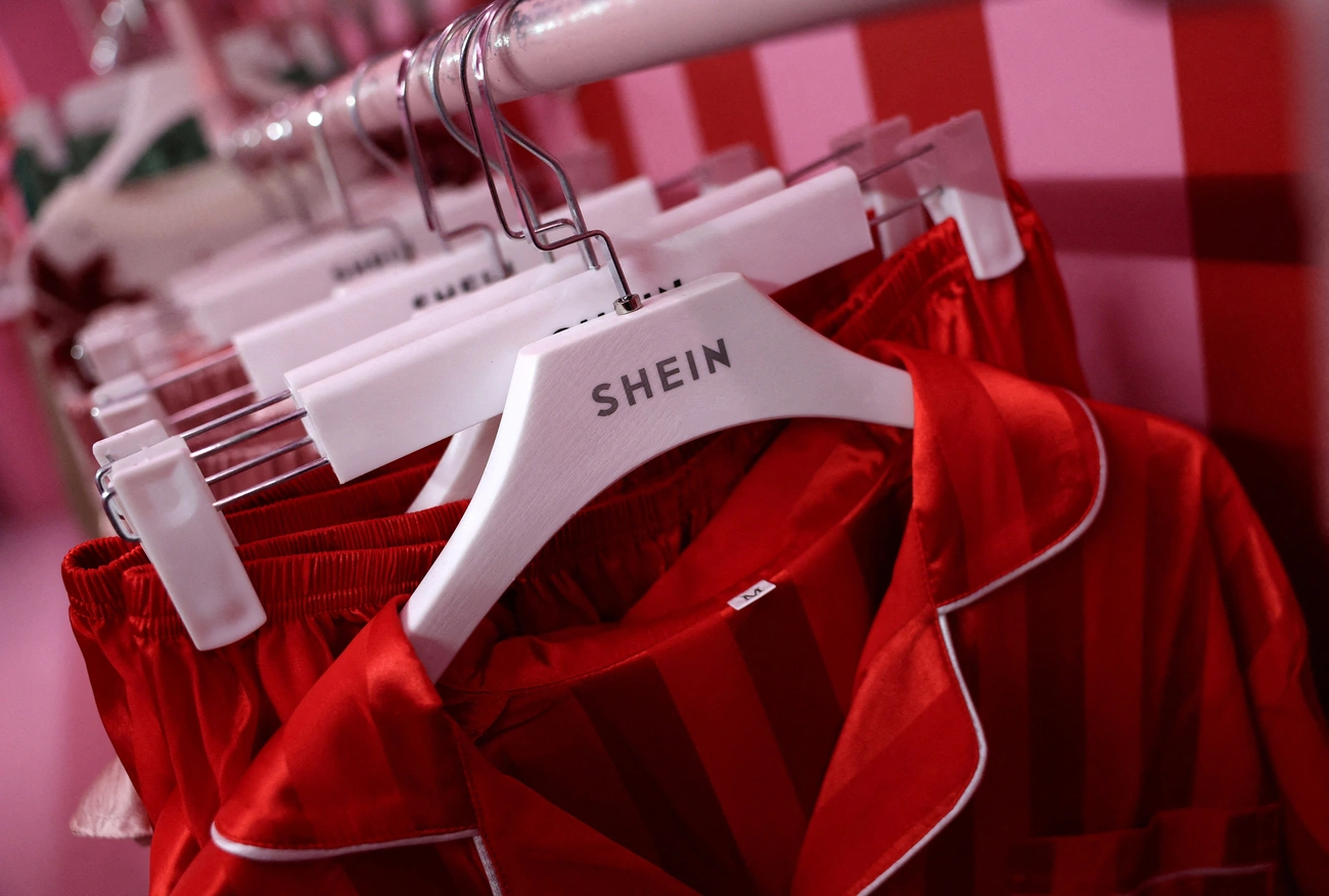 Red striped clothing hanging on white Shein-branded hangers in a retail setting.