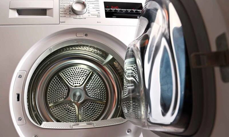 Front-loading white dryer with open door showing stainless steel drum and control panel above