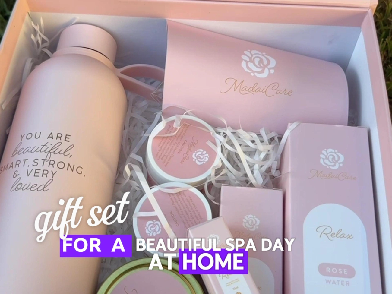 Luxury pink spa gift basket including water bottle, mug, rose water, and skincare products for a relaxing day at home.