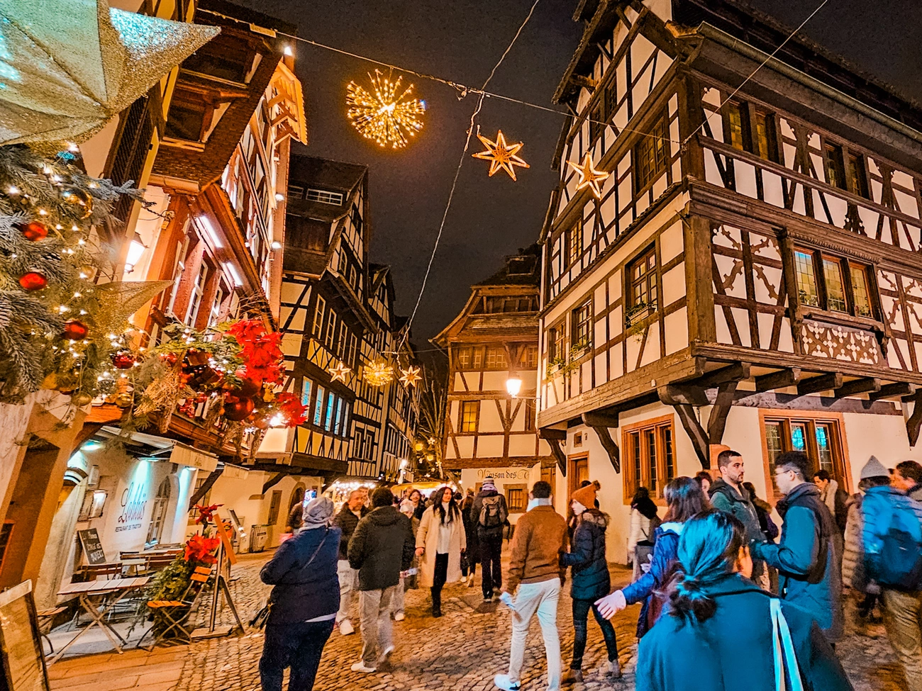 Crowded street at Strasbourg Christmas Market 2025 with traditional timber-framed buildings and festive lights at night.